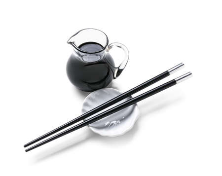 Jug of soy sauce and chopsticks on white backgroundの写真素材