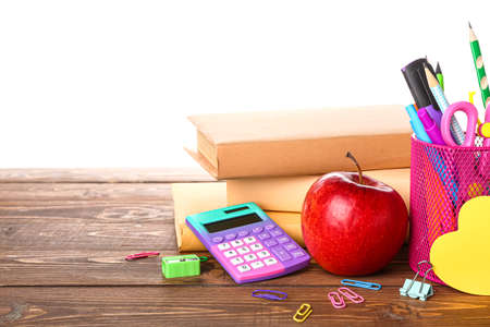 School stationery with apple on wooden table against white backgroundの写真素材