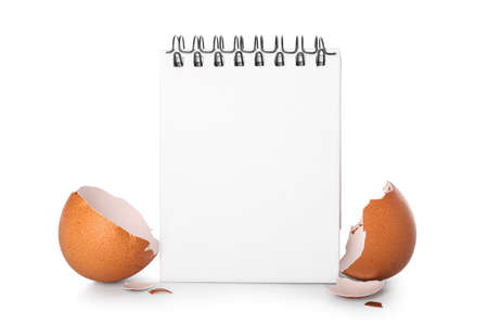 Blank notebook with broken eggshell on white background