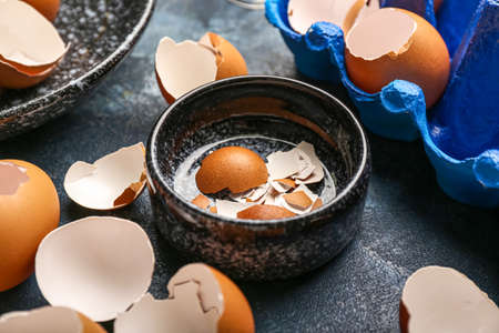 Bowl with broken egg shells on color table, closeup