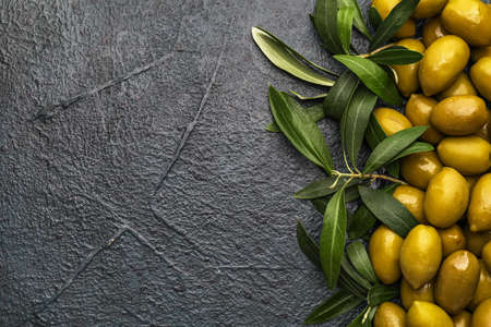 Heap of tasty green olives and leaves on dark backgroundの写真素材