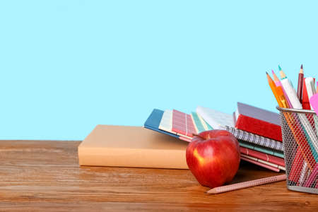 School stationery with apple on table against blue background