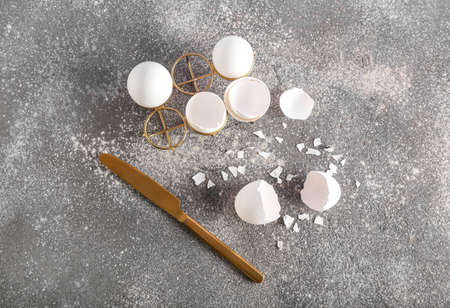 Holder with broken egg shells and knife on dark background