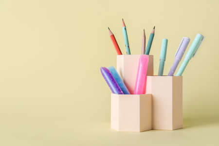 Cups with pens, pencils and glitters on beige backgroundの写真素材