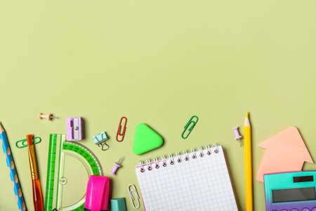 Different school stationery on green background, top view