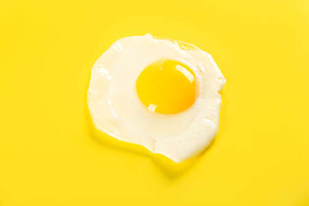 Tasty fried egg on yellow background