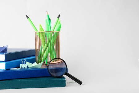 Cup with school stationery and books on light backgroundの写真素材
