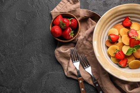 Plate with mini pancakes and strawberry on dark background, closeupの写真素材
