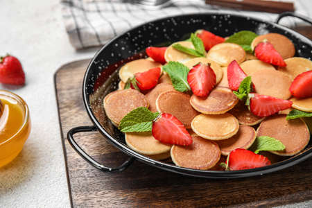 Mini pancakes, strawberry and honey on light table, closeup