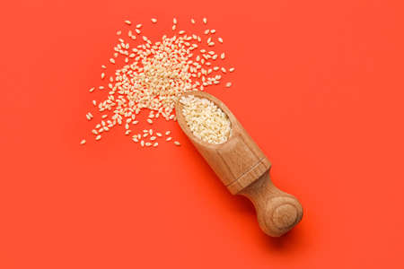 Wooden scoop with sesame seeds on red backgroundの写真素材