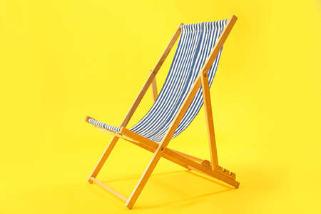 Wooden deck chair on yellow background