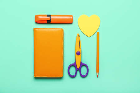 Set of stationery with scissors on color background