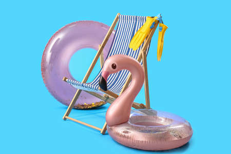 Wooden deck chair with inflatable rings and paddles on blue backgroundの写真素材
