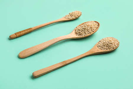 Wooden spoons with sesame seeds on green backgroundの写真素材