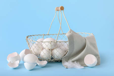 Basket with white chicken eggs on color background