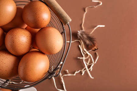 Basket with brown chicken eggs on color background, closeup