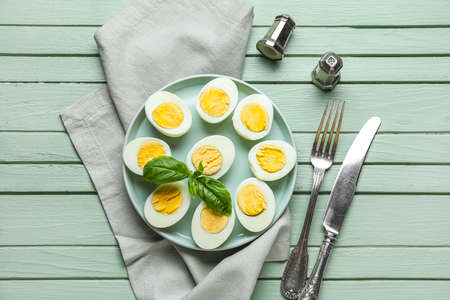 Composition with plate of boiled chicken eggs, spices and cutlery on color wooden backgroundの写真素材