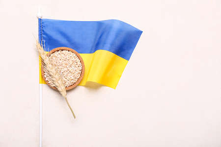 Bowl with wheat grains, spikelet and flag of Ukraine on light backgroundの写真素材
