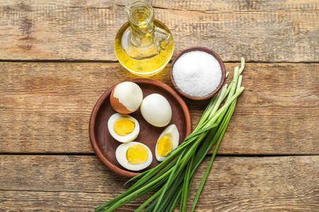 Bowl with boiled chicken eggs, oil, salt and green onion on wooden background