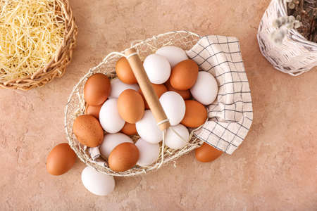 Basket with chicken eggs on beige background