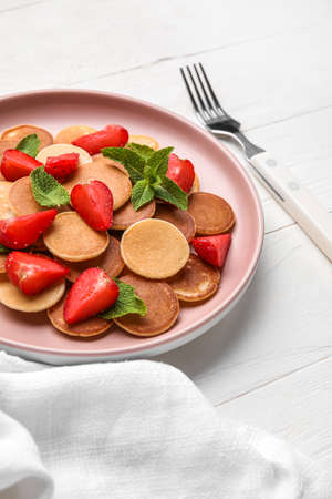 Plate with mini pancakes and strawberry on light wooden backgroundの写真素材