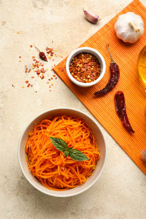 Composition with bowl of korean carrot salad and ingredients on light backgroundの写真素材