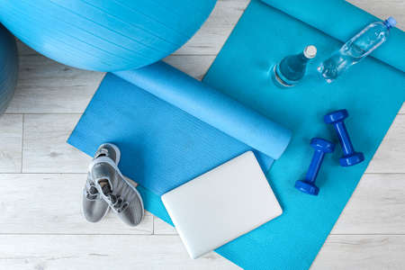 Laptop and sports equipment on yoga matの写真素材