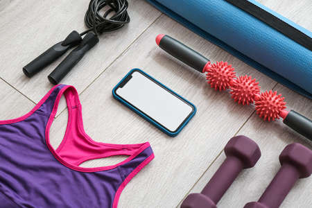 Mobile phone, female top and sports equipment on gray wooden backgroundの写真素材