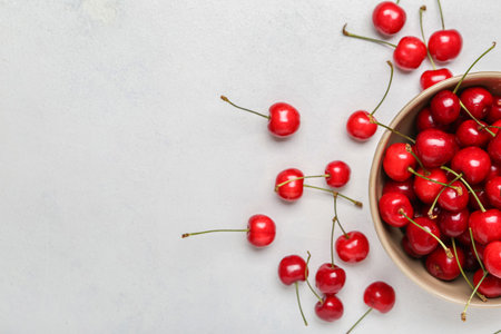 Bowl of sweet cherry on light backgroundの写真素材
