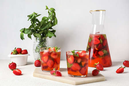 Board with glasses of strawberry lemonade on white background