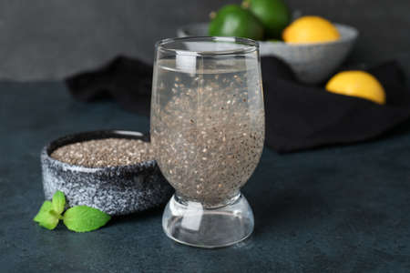 Glass of healthy drink and bowl with chia seeds on dark tableの写真素材