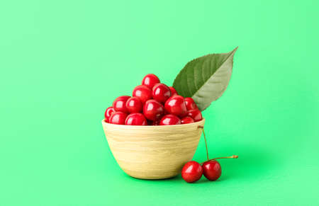 Bowl of sweet ripe cherries on green backgroundの写真素材