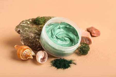 Composition with jar of spirulina facial mask, seashells and stones on color backgroundの写真素材