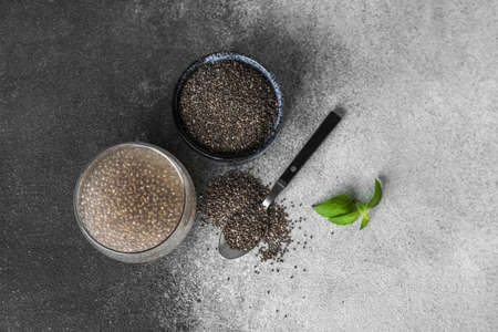 Glass of water with chia seeds on black and white background