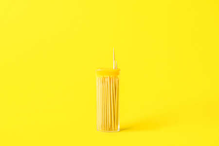 Holder with wooden toothpicks on yellow background