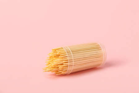 Box with wooden toothpicks on pink background
