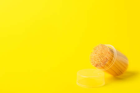 Plastic holder with toothpicks on yellow background