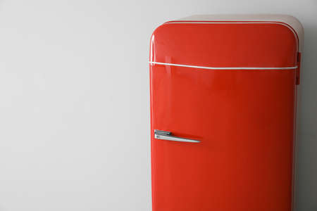 Stylish retro fridge near light wall