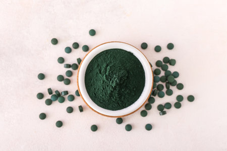 Bowl of green spirulina powder and pills on white backgroundの写真素材