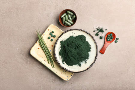 Plates of spirulina powder, spoon and pills on gray backgroundの写真素材
