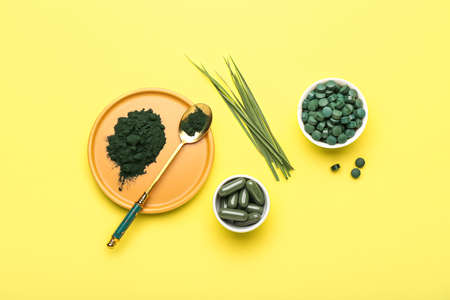 Plate of spirulina powder, spoon and bowls on yellow backgroundの写真素材