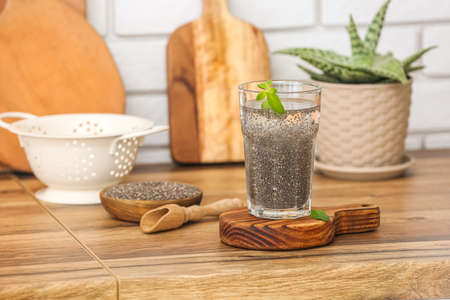 Glass of water, scoop and bowl with chia seeds on counter in kitchenの写真素材