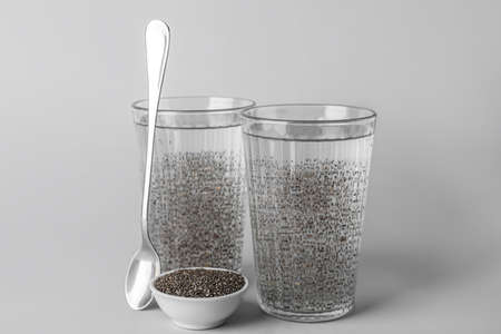 Glasses of water and bowl with chia seeds on light backgroundの写真素材