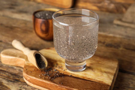 Glass with water and chia seeds on board against wooden backgroundの写真素材