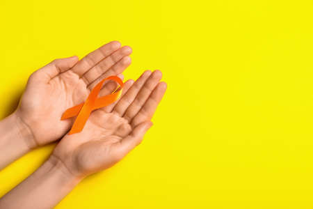 Woman with orange awareness ribbon on yellow background. Kidney cancer conceptの写真素材