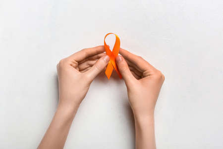 Woman with orange awareness ribbon on white background. Kidney cancer concept