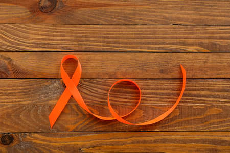 Orange awareness ribbon on wooden background. Kidney cancer conceptの写真素材