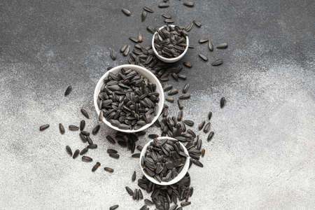 Bowls of sunflower seeds on black and white background