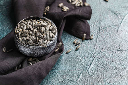 Bowl of black sunflower seeds and napkin on dark background