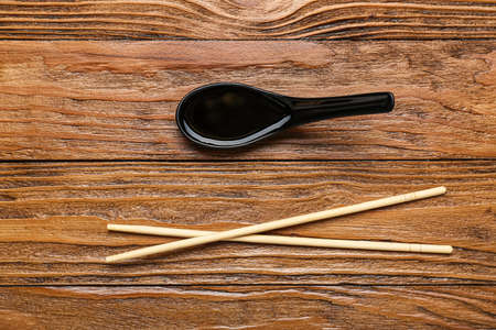 Spoon of soy sauce and chopsticks on wooden backgroundの写真素材